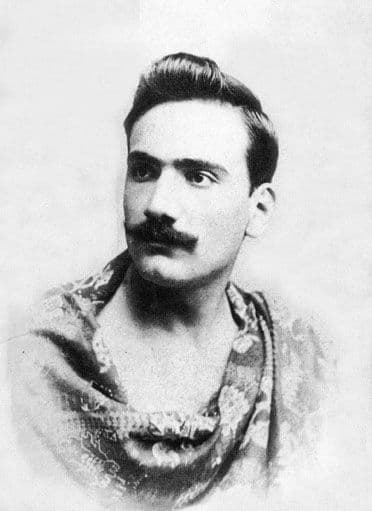 Enrico Caruso in one of his first publicity photos, taken in Sicily 1896 at the age of 24; he is wearing a bedspread draped like a toga since his only dress shirt was at the laundry